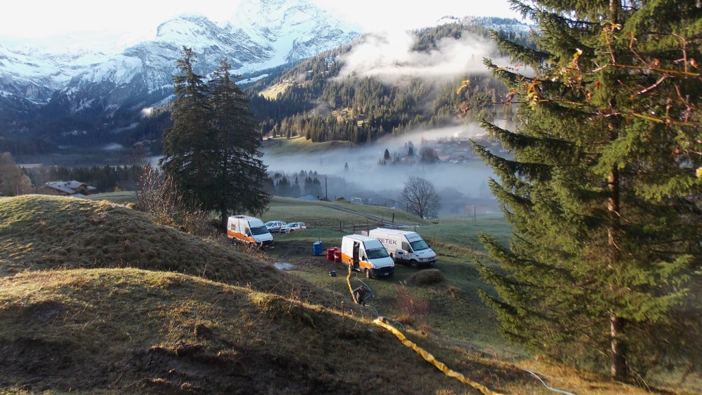 Baustellenfahrzeuge in alpiner Landschaft während Arbeiten zur Anhebung eines Chalets